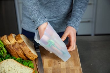Bir kadın öğle yemeği hazırlar ve plastik poşetleri değiştirmek için sıfır atık yaşam tarzının bir parçası olarak yiyecek kalitesinde bir silikon torbaya sandviç koyar.