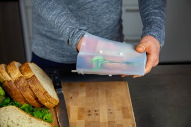 Bir kadın öğle yemeği hazırlar ve plastik poşetleri değiştirmek için sıfır atık yaşam tarzının bir parçası olarak yiyecek kalitesinde bir silikon torbaya sandviç koyar.