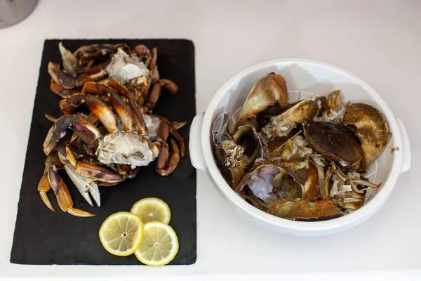 Dungeness crab legs are cleaned and prepared to be cooked for dinner. Crab guts and shells are discarded in a bowl beside them.