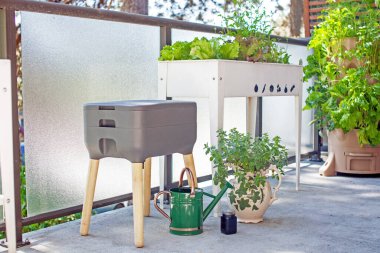 Vermigübreleme sistemi (solucan gübresi) bir apartmanın balkonunda diğer teras çiftçileriyle birlikte bulunur. Solucanlar yiyecek artıklarını yerler ve gübre olarak kullanmak için solucan atıkları ve solucan çayı üretirler. Atıkları yeniden yönlendir.