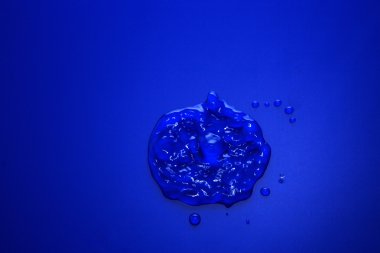 Büyük bir damla su içinde ve çevresinde mavi üzerinde küçük damlacıklar
