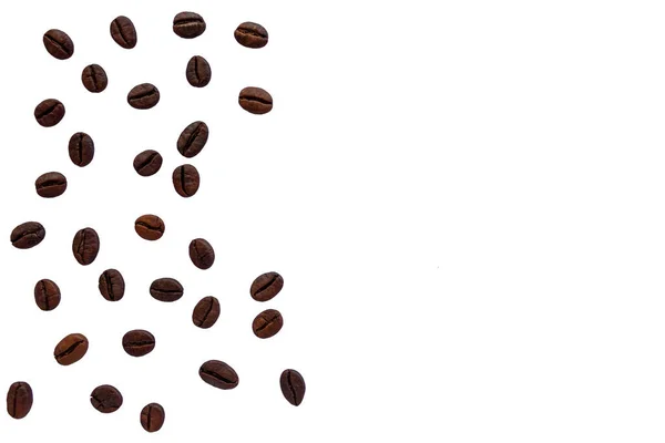 Beyaz arka planda kaotik bir şekilde duran kahve çekirdekleri..