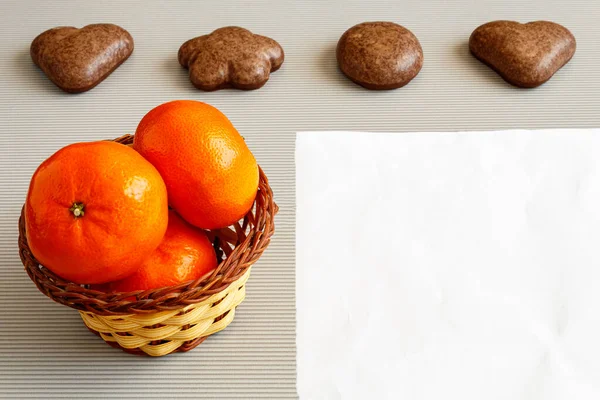 Sepette mandalinalar ve arka planda beyaz çarşaflı zencefilli kurabiyelerin yanında.