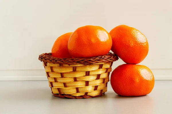 Hasır sepetin içinde hafif arkaplanda mandalinalar.