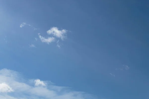 Açık mavi gökyüzüne karşı beyaz bulutlar.