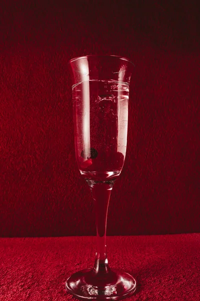 Versez dans un verre avec des baies rouges. Fond rouge foncé. — Photo