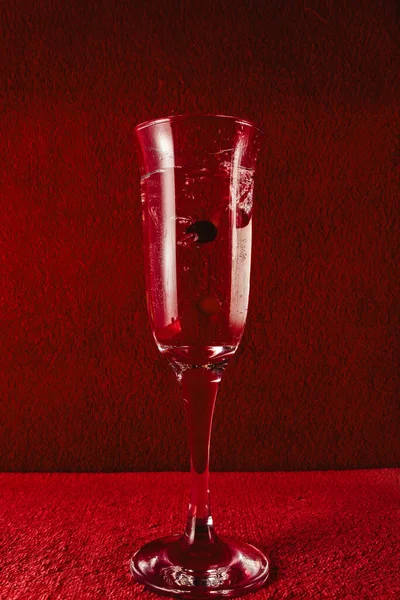 Kırmızı böğürtlenli bir bardağa su sıçrat. Koyu kırmızı arkaplan.