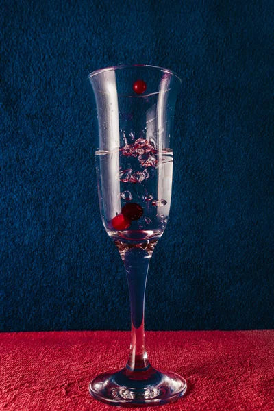 Kırmızı böğürtlenli bir bardağa su sıçrat. Koyu mavi arkaplan.