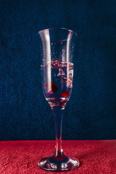 Kırmızı böğürtlenli bir bardağa su sıçrat. Koyu mavi arkaplan.