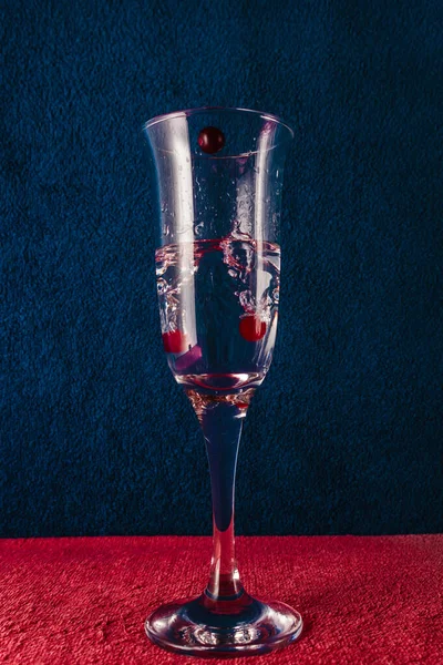 Splash in a glass with red berries. Dark blue background. — Stock Photo, Image