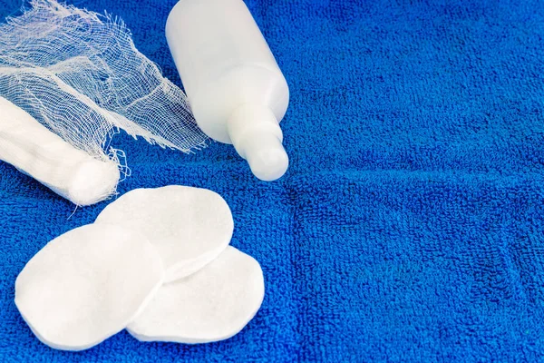 Pamuk yastıklı hidrojen peroksit ve mavi arka planda bandaj..