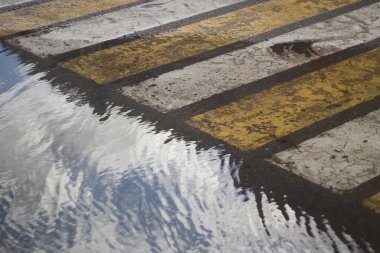 Yaya geçidinde su birikintisi. Şehirdeki yol. Sokakta yol işaretleri.