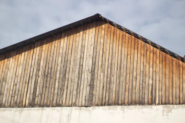 Het dak van het gebouw. Plankdak op betonnen fittingen. Oud huis. Blanco muur. Ridge dak type. — Stockfoto