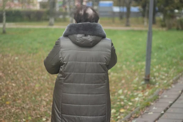 Una anciana solitaria en la calle. Mujer con chaqueta de invierno. Existencia humana socialmente descuidada. — Foto de Stock