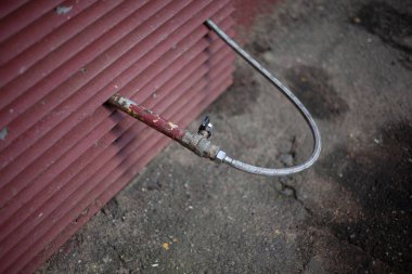 Ev yapımı su hortumu. Kuyudan su bu hortumdan akıyor. Bir kır evinde su borusu. Sulama sistemi duvardan çıkıyor.. 