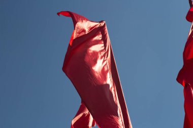 Kırmızı bayraklar. Rüzgarda savrulan kırmızı madde. Gökyüzünün arka planında bayraklar.