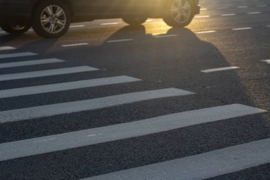 Otobandan yaya geçidi. Yaya işaretli asfalt yüzeyde gün batımı.