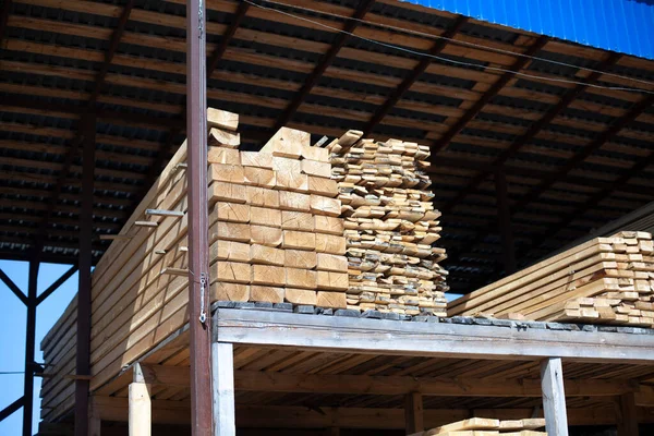 Lots of boards in the warehouse. Bars of wood are stacked. Building materials. Products of the timber processing industry.