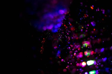 Renkli su dokusu. Farklı renklerde yanan su damlaları. Çeşmeden yakın plan su çekimi. Parlak renkler su akış arkaplanı.