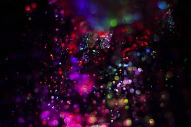 Renkli su dokusu. Farklı renklerde yanan su damlaları. Çeşmeden yakın plan su çekimi. Parlak renkler su akış arkaplanı.