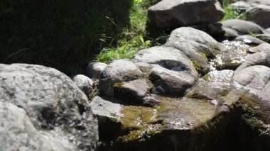 Taşların üzerinden su akıyor. Alp kaydırağındaki taşların arasında bir dere. Bahçede peyzaj. Çakıl taşları arasında su akıntısı.