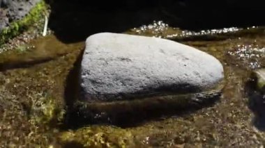 Taşların üzerinden su akıyor. Alp kaydırağındaki taşların arasında bir dere. Bahçede peyzaj. Çakıl taşları arasında su akıntısı.
