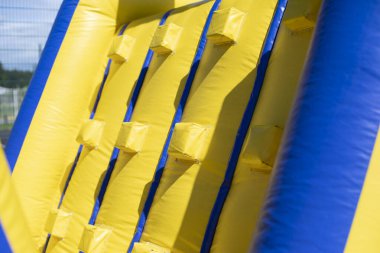 Şişirilebilir engelli koşu parkuru. Parktaki şişme bina. Çocukların mutluluğu için bir yer. Oyun parkı. Ama sarı-mavi.