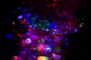 Renkli su dokusu. Farklı renklerde yanan su damlaları. Çeşmeden yakın plan su çekimi. Parlak renkler su akış arkaplanı.