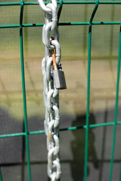Chain on the fence. A metal chain hangs on the fence. Fence enclosing the territory with a lock and chain for blocking.