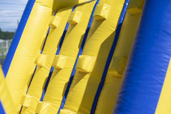 Şişirilebilir engelli koşu parkuru. Parktaki şişme bina. Çocukların mutluluğu için bir yer. Oyun parkı. Ama sarı-mavi.