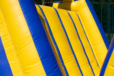 Şişirilebilir engelli koşu parkuru. Parktaki şişme bina. Çocukların mutluluğu için bir yer. Oyun parkı. Ama sarı-mavi.