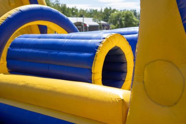 Şişirilebilir engelli koşu parkuru. Parktaki şişme bina. Çocukların mutluluğu için bir yer. Oyun parkı. Ama sarı-mavi.