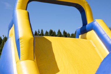 Şişirilebilir engelli koşu parkuru. Parktaki şişme bina. Çocukların mutluluğu için bir yer. Oyun parkı. Ama sarı-mavi.