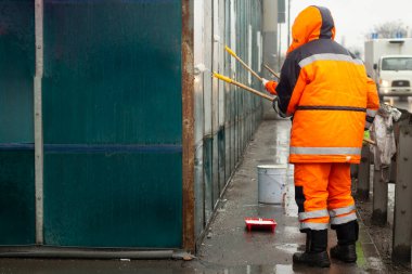 Ressam beyaz boyayla resim yapar. Boyayla grafiti yapıyor. Duvarı boyuyorum. Bir işçi, vandalist bir yazının üstünü boyuyor..