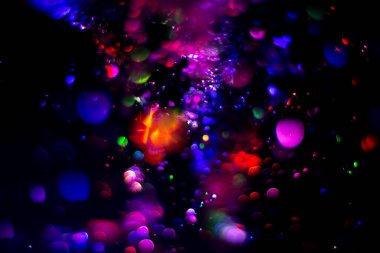 Renkli su dokusu. Farklı renklerde yanan su damlaları. Çeşmeden yakın plan su çekimi. Parlak renkler su akış arkaplanı.