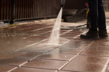 Koşu bandını bir jet suyla yıkıyor. Adam yoldaki kiri temizliyor. Çiti ve kaldırımı tozdan temizliyorum..