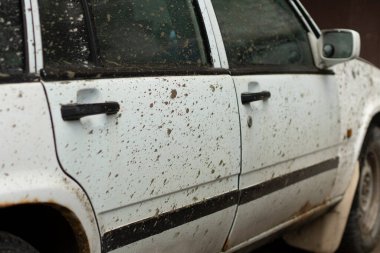 Kirli bir araba yıkılıyor. Çamurla kaplı beyaz bir araba. Araba şehirde, suyun altında..