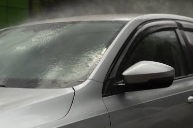 Araba yıkama. Araba bir su püskürtüsünün basıncıyla yıkanır. Arabanın yüzeyindeki kiri temizlemek için su spreyi kullanmışlar..