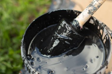 Kovadaki boya fırçası. Ahşap için siyah boya. Su bazlı kalın bir boya tabakasını fırçala.