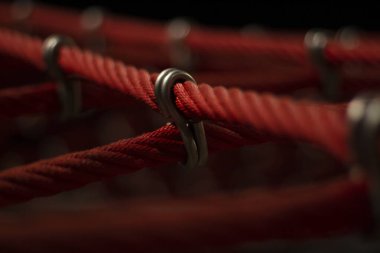 Oyun parkındaki ipler. Tırmanma ağı, yakın çekim. Halatlar halatlarla bağlandı. Gece sokak ışıklarında ip desenli çekim.