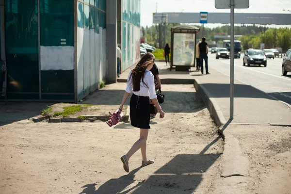 少女は道路の脇を歩いている スカートを着た女の子が通りを歩いている 歩道が整備されていない道路で人が歩くもの — ストック写真