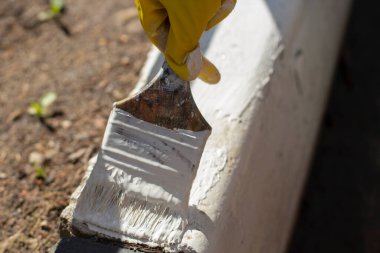 Kaldırımı beyaz boyayla boyuyor. Yoldaki kaldırım için boya ile fırçala. Yolu boyuyorum. Eldivenli adam resim yapıyor..