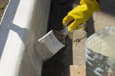 Kaldırımı beyaz boyayla boyuyor. Yoldaki kaldırım için boya ile fırçala. Yolu boyuyorum. Eldivenli adam resim yapıyor..