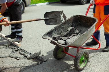 İnşaat atığı vagonu. Asfaltı kürekle arabaya koyuyor. Bir işçi asfalt bırakıyor. Yol tamiri. Eski asfaltın tahrip edilmesi.