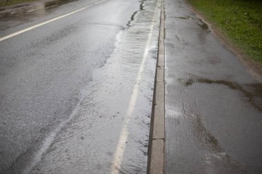Dart üzerinde bir çayır. Yolun kenarı yağmurla dolmuş. Yol boyunca çok su akar..