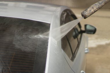 Araba yıkama. Araba bir su püskürtüsünün basıncıyla yıkanır. Arabanın yüzeyindeki kiri temizlemek için su spreyi kullanmışlar..