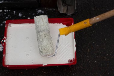 Konteynırdaki beyaz boya. Duvarı boyamak için boyalı rulo..