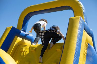 Çocuklar şişme bir kaydırağa tırmanır. Şişirilebilir engelli koşu parkuru. Çocuklar için aktif dinlenme. Şişme oyun parkı. Spor ve eğlence..