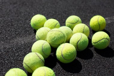 Tenis topları. Toplar oyun alanının yüzeyinde yatıyor. Topla tenis oynuyorum. Raket vuruşu için yeşil yumuşak toplar.