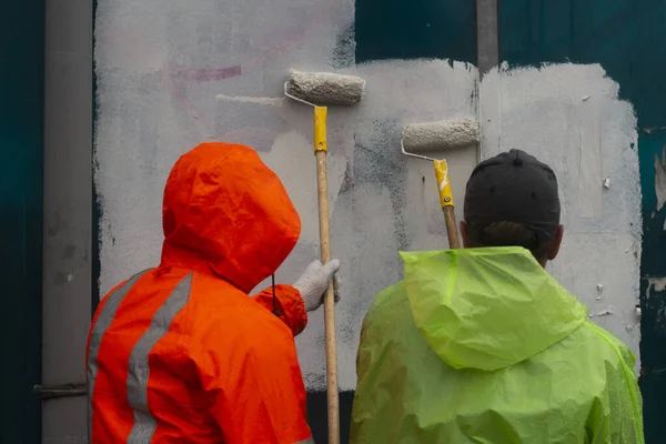 Ressam beyaz boyayla resim yapar. Boyayla grafiti yapıyor. Duvarı boyuyorum. Bir işçi, vandalist bir yazının üstünü boyuyor..